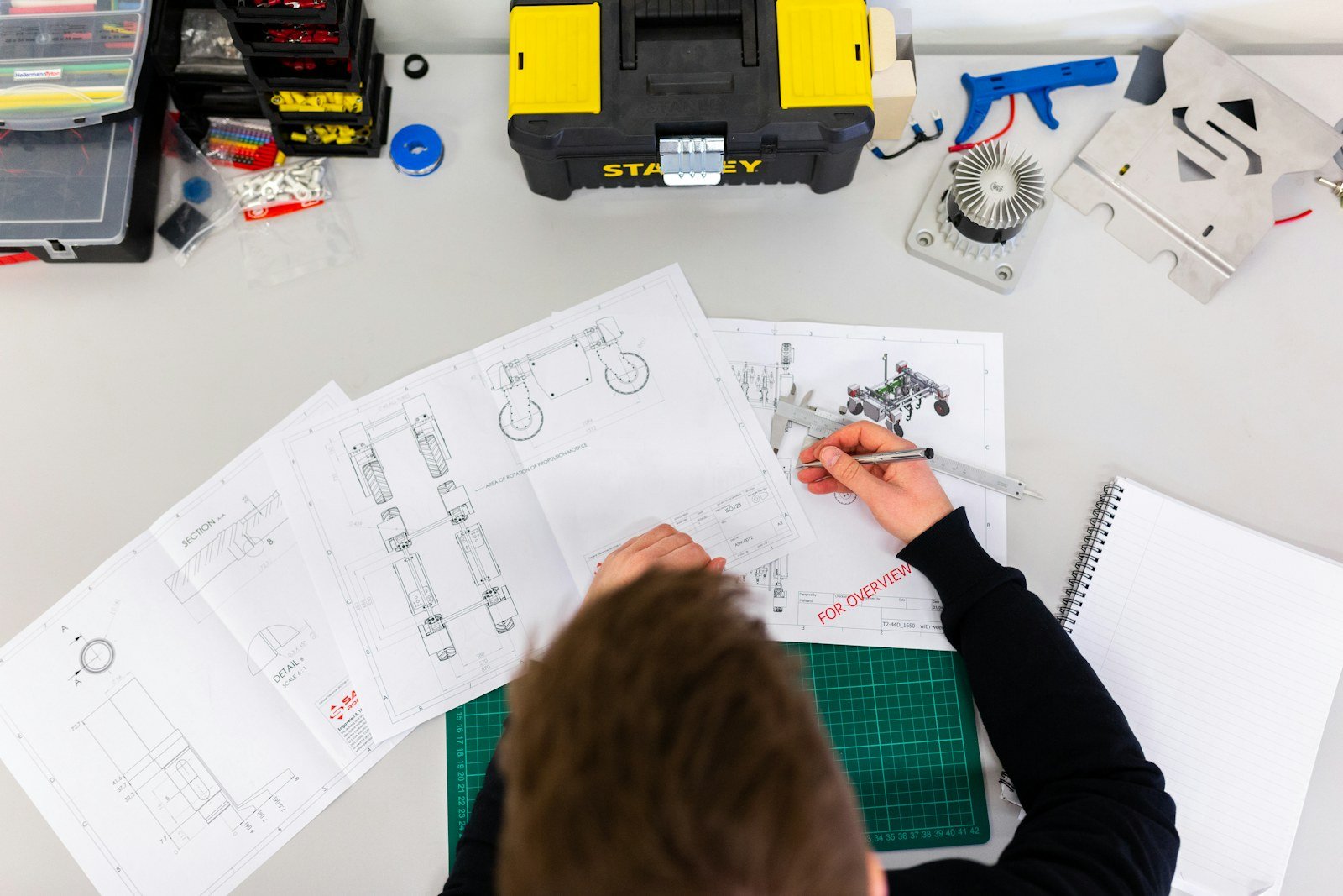 Engineering drawings and a prototype on a workbench